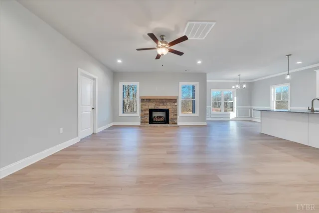 an empty room with wooden floor fireplace and windows