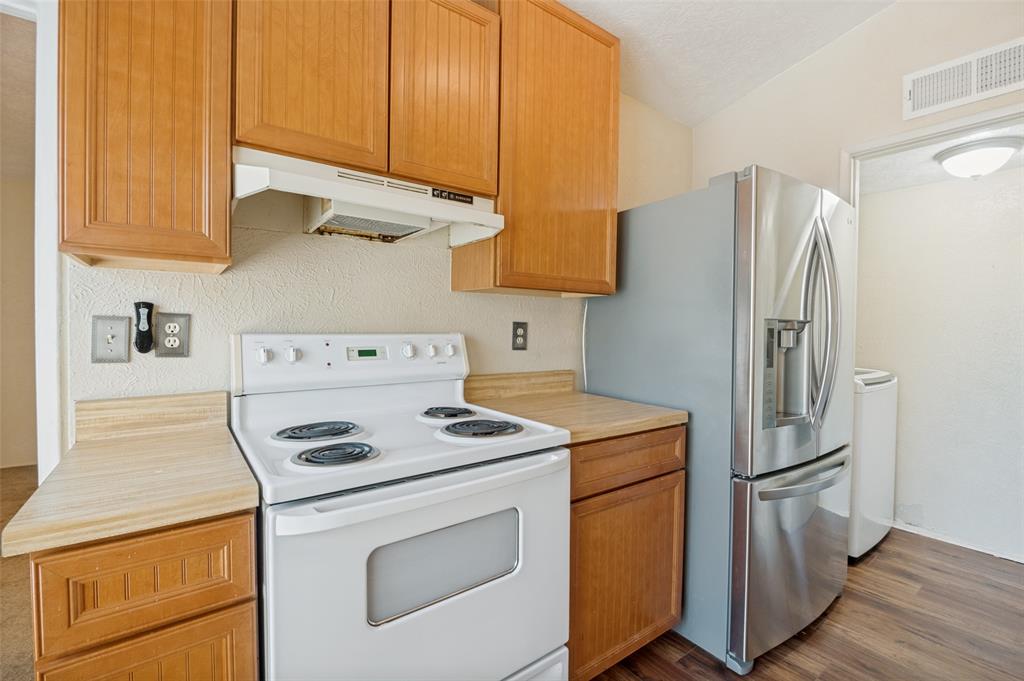 7305 Pineberry Road Dallas, TX 75249 - Photo 13 of 25 a kitchen with stainless steel appliances white cabinets and a refrigerator