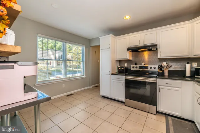 a kitchen with granite countertop a stove a sink and a microwave