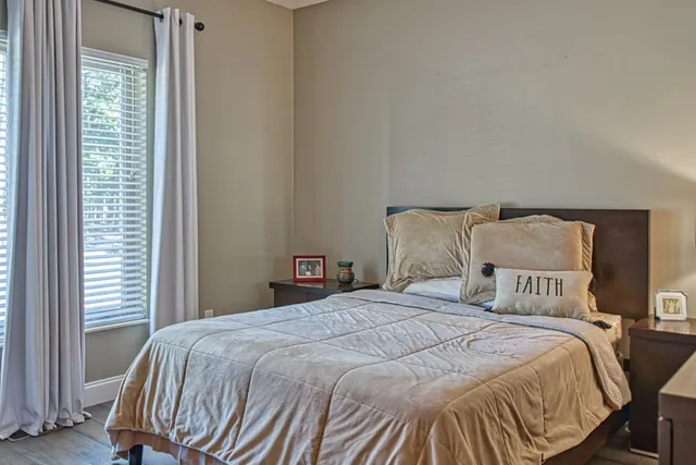 a bed sitting in a bedroom next to a window with potted plants