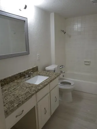 a bathroom with a granite countertop sink a toilet and bathtub