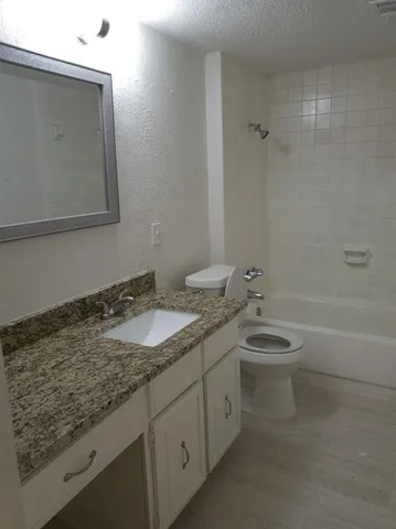 a bathroom with a granite countertop sink a toilet and bathtub