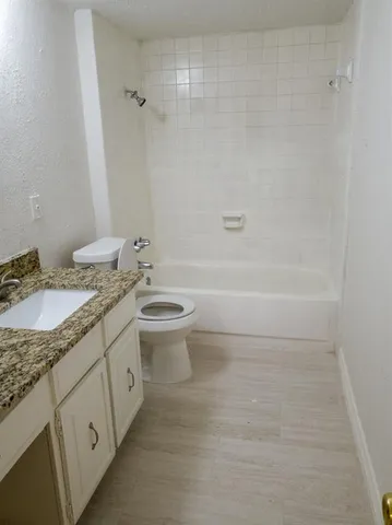 a bathroom with a granite countertop sink a toilet and bathtub