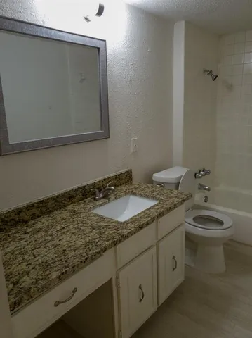 a bathroom with a granite countertop sink and a toilet