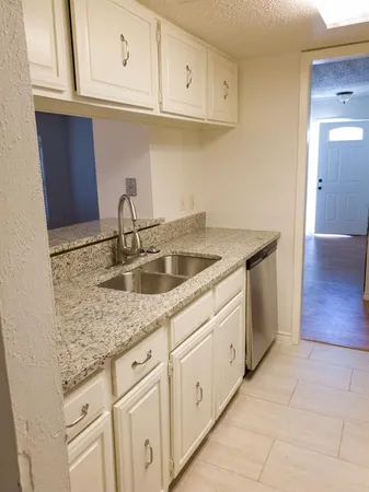 a kitchen with stainless steel appliances granite countertop a sink dishwasher and cabinets with wooden floor
