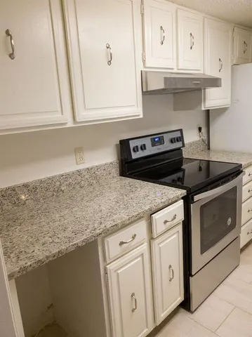 a kitchen with granite countertop white cabinets and a stove