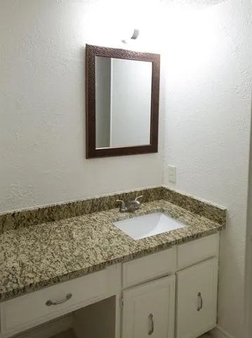 a bathroom with a granite countertop sink and vanity
