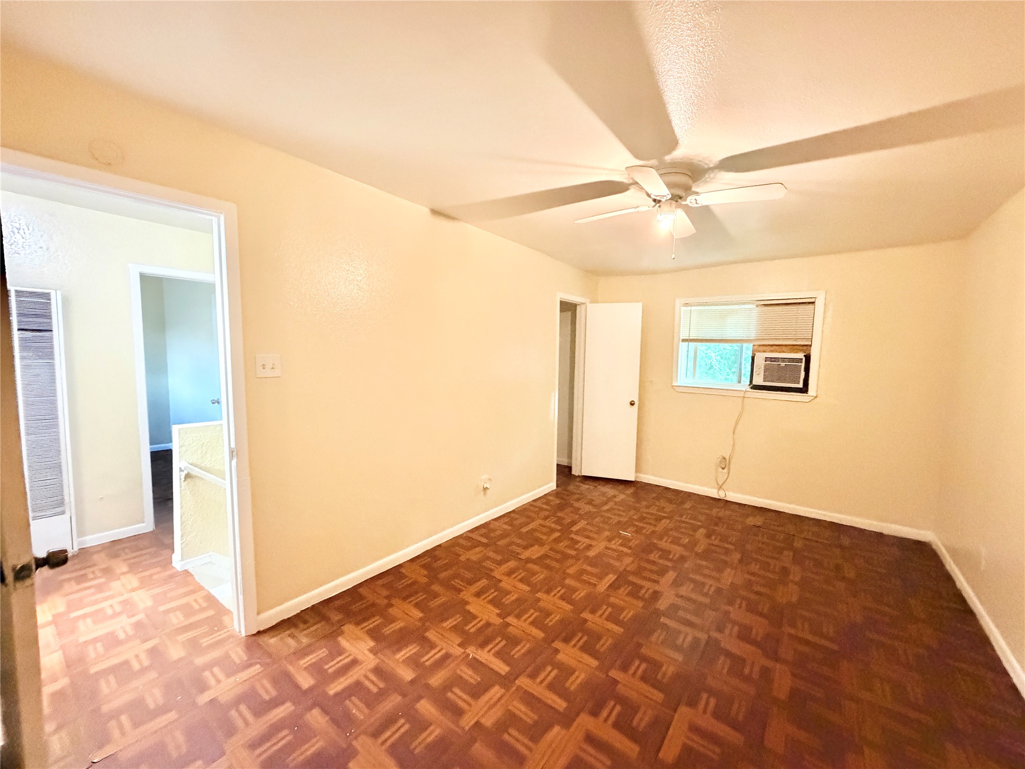 6257 Manor Road, Unit B Austin, TX 78723 - Photo 23 of 38 Room featuring wood-finish parquet flooring, a ceiling fan with integrated lighting, and a window with blinds
