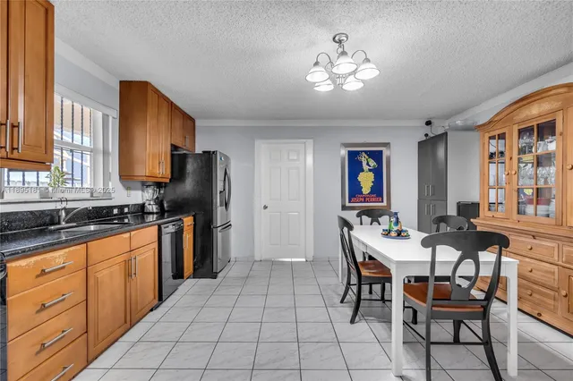 a kitchen with stainless steel appliances granite countertop a sink dishwasher a dining table and chairs with wooden floor