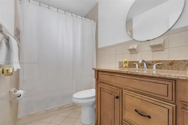 a bathroom with a granite countertop toilet sink mirror and vanity