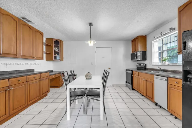 a open kitchen with stainless steel appliances granite countertop a stove a sink and a microwave