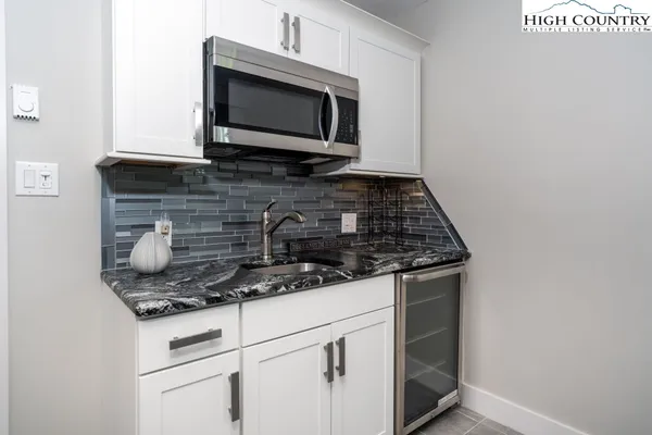 a kitchen with granite countertop white cabinets stainless steel appliances and a microwave