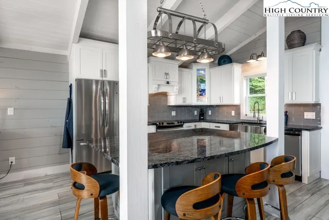 a kitchen with stainless steel appliances granite countertop a sink a stove and a wooden floors