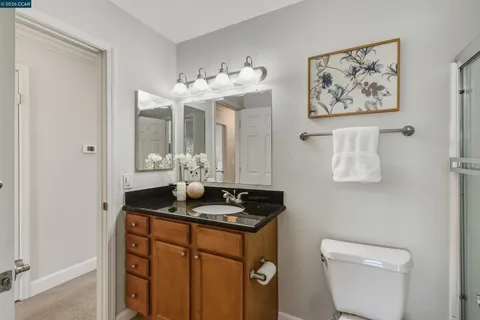 a bathroom with a granite countertop sink mirror and toilet