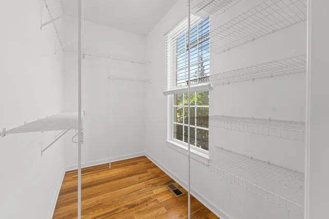 a view of empty room with wooden floor and fan