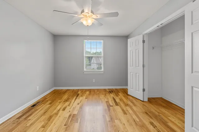 a view of empty room with wooden floor and fan