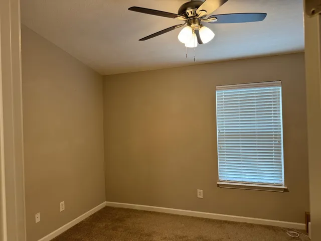 an empty room with a window and a fan