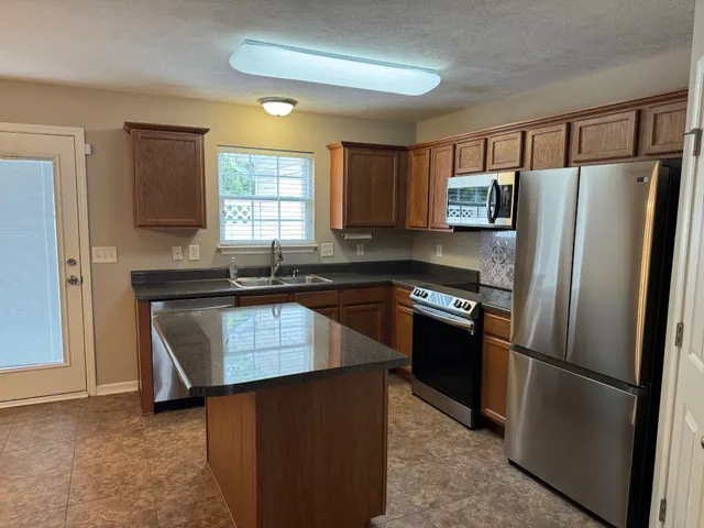 a kitchen with granite countertop a refrigerator and a sink