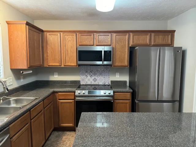 a kitchen with stainless steel appliances granite countertop a refrigerator stove and microwave