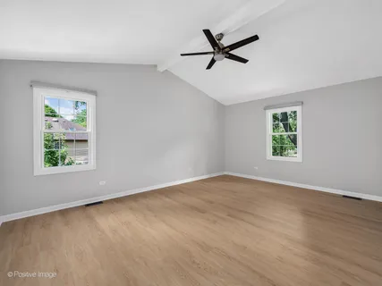 a view of a big room with wooden floor a ceiling fan and windows