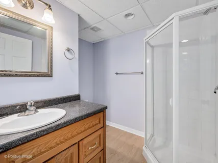 a bathroom with a granite countertop sink a mirror and a shower