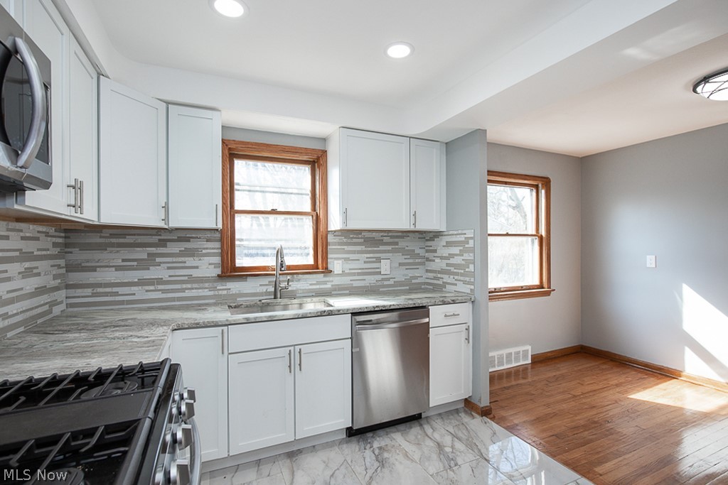 2231 Lorimer Road Cleveland, OH 44134 - Photo 11 of 28 Kitchen with light tile flooring, stainless steel appliances, sink, light stone counters, and tasteful backsplash