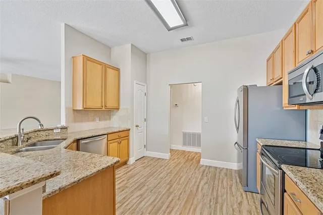 a kitchen with stainless steel appliances granite countertop a sink refrigerator and cabinets