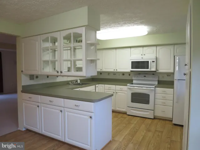 a kitchen with granite countertop white cabinets and white appliances