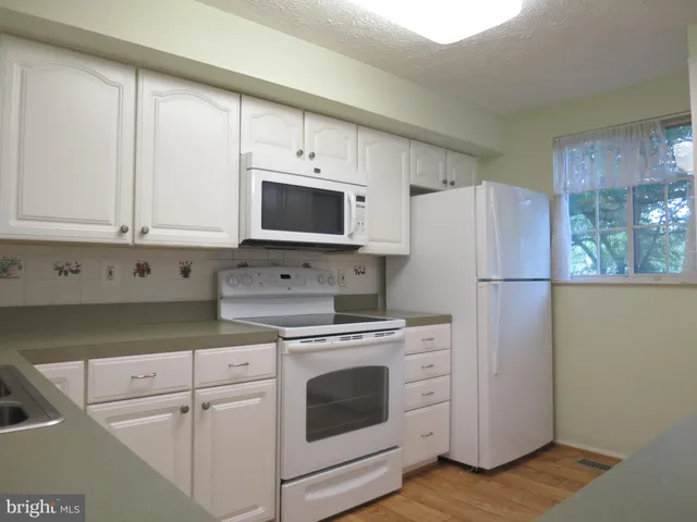a kitchen with cabinets stainless steel appliances and wooden floor