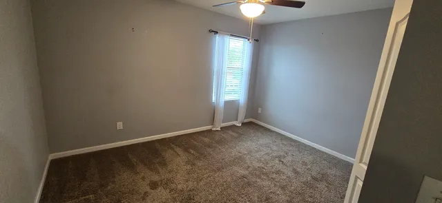 an empty room with windows and chandelier fan