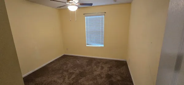 an empty room with a window and a ceiling fan