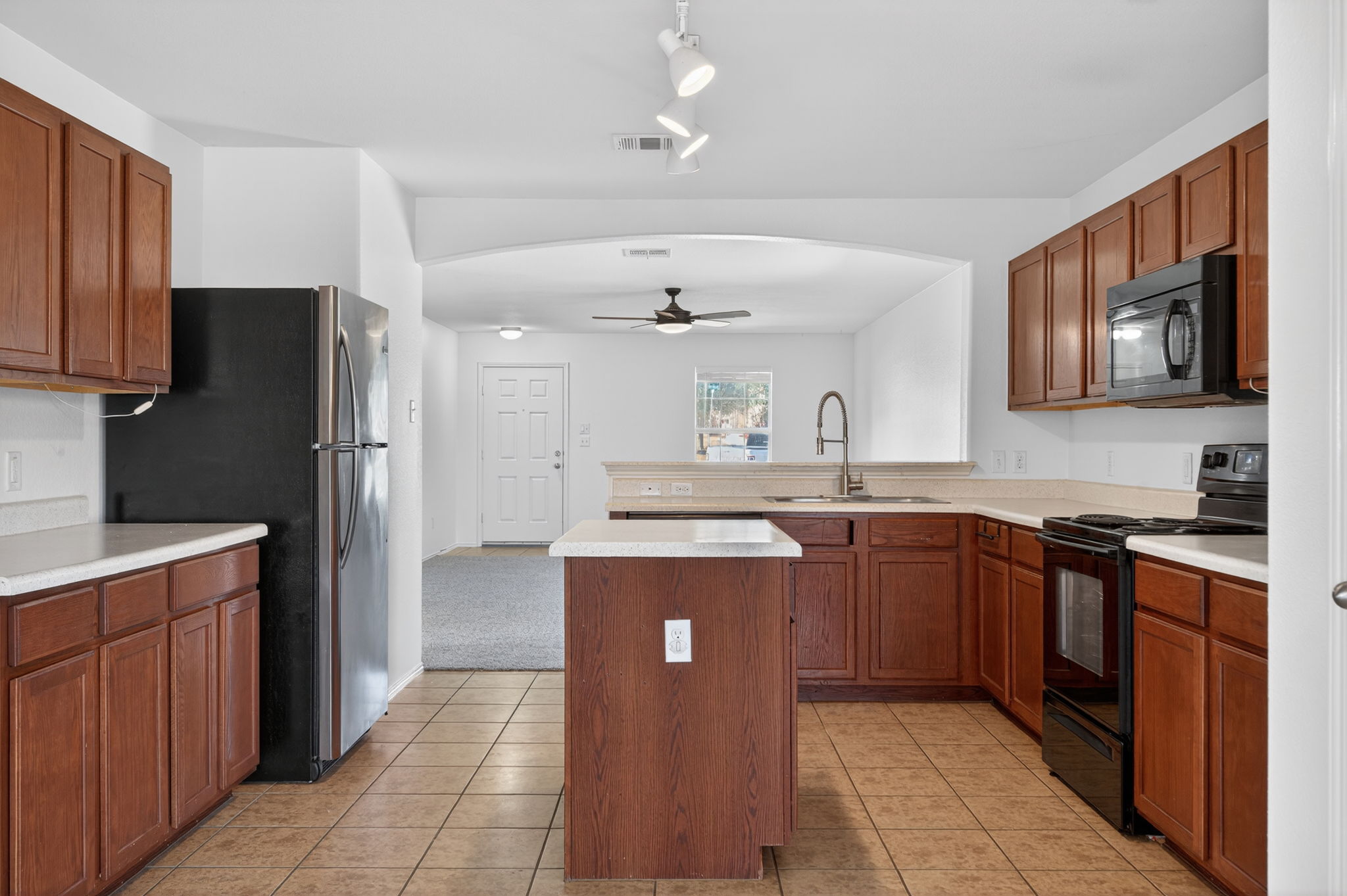 13629 Coomer Path Pflugerville, TX 78660 - Photo 10 of 30 Kitchen with black appliances, ceiling fan, light countertops, wood finish cabinetry, and track lighting