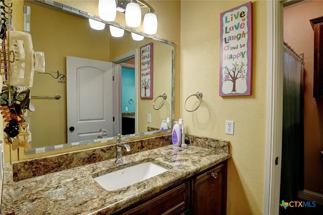 a bathroom with a granite countertop sink and a mirror