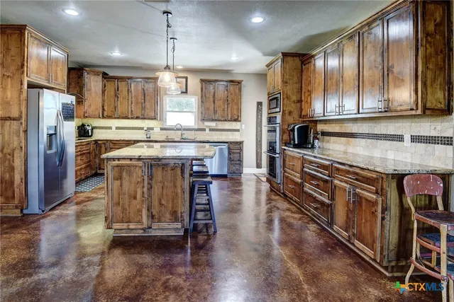 a kitchen with stainless steel appliances granite countertop wooden cabinets a stove top oven a sink and dishwasher