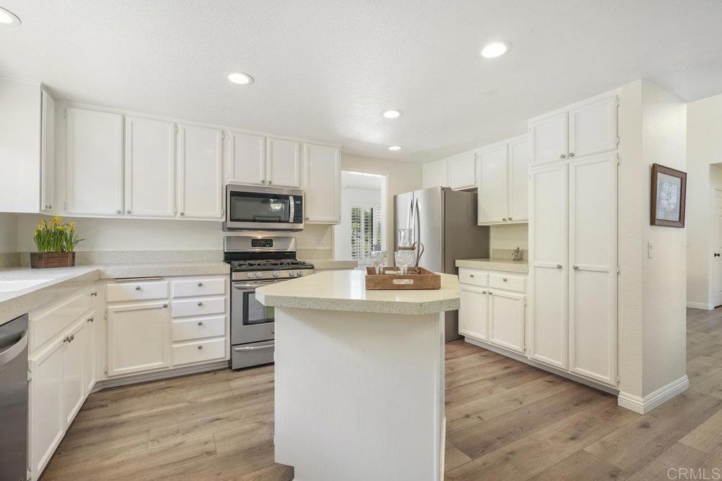 1729 Pinehurst Avenue Escondido, CA 92026 - Photo 4 of 29 a kitchen with stainless steel appliances kitchen island granite countertop a stove top oven a refrigerator a sink and white cabinets with wooden floor