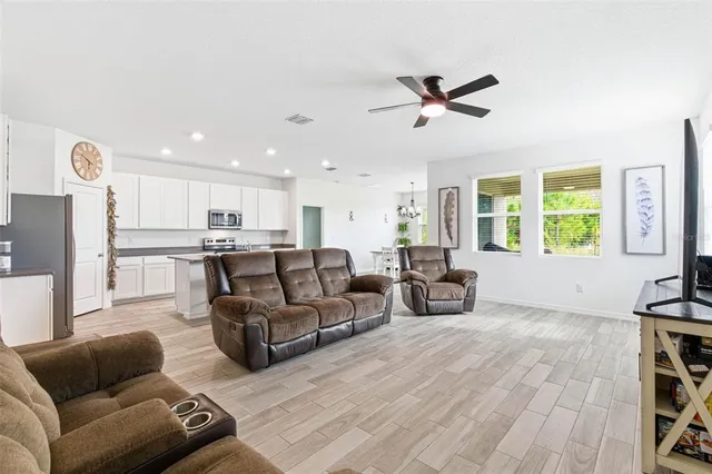 a living room with furniture kitchen view and a chandelier