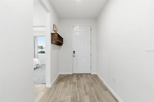 a view of a hallway with wooden floor and a bathroom