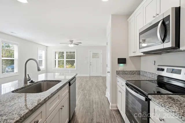 a kitchen with granite countertop a sink stainless steel appliances and cabinets