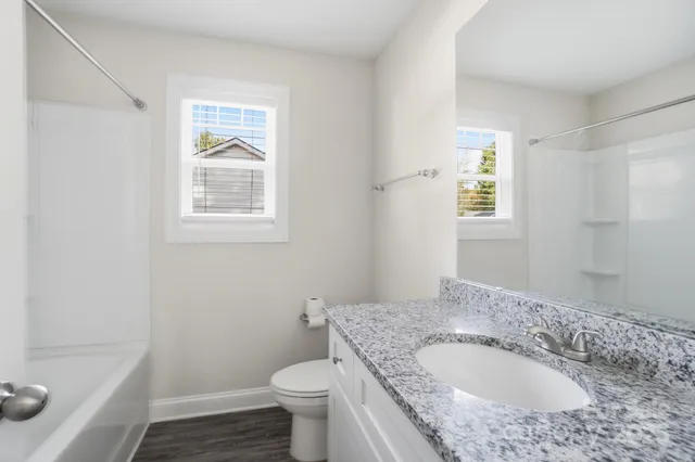 a bathroom with a granite countertop sink a toilet and tub