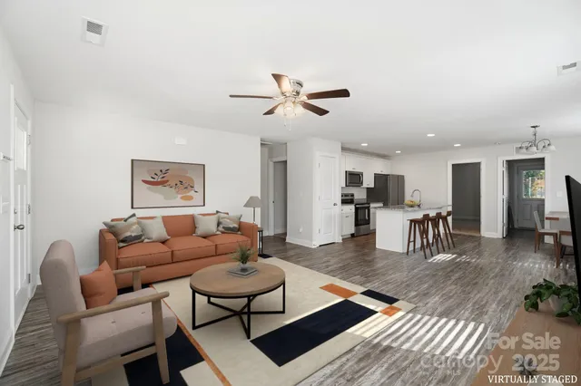 a living room with furniture a table and kitchen view