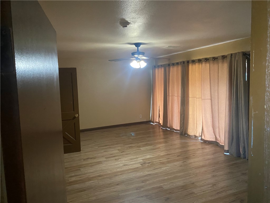 5335 East Riverview Street Robstown, TX 78380 - Photo 10 of 17 an empty room with wooden floor chandelier fan and windows