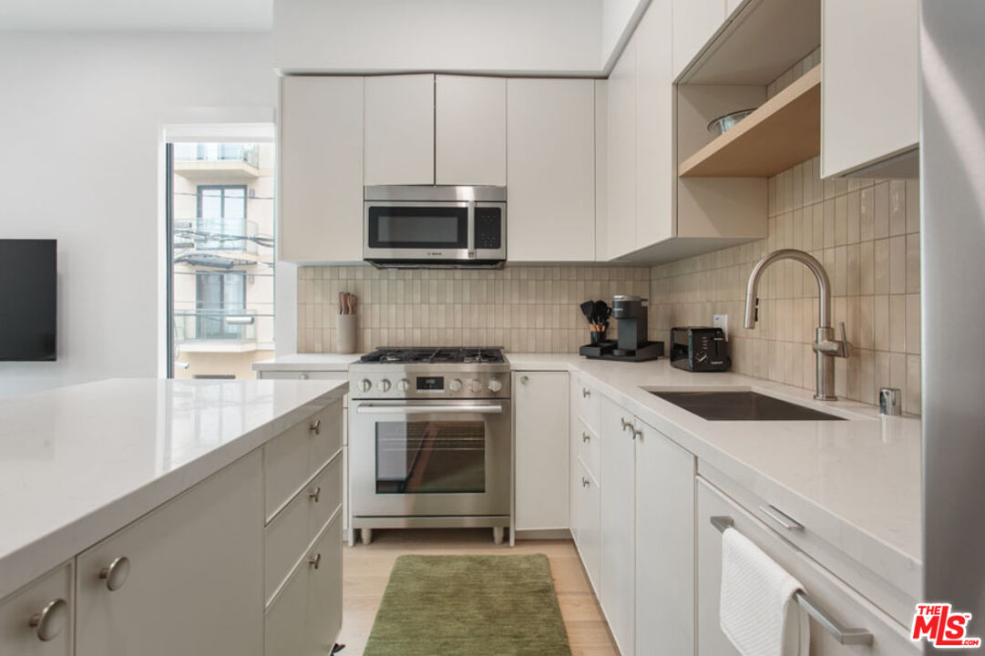 10310 Santa Monica Boulevard, Unit PH710 Los Angeles, CA 90025 - Photo 2 of 38 a kitchen with stainless steel appliances granite countertop a sink a stove a microwave a refrigerator a counter space and cabinets