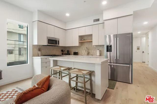 a kitchen with stainless steel appliances white cabinets and wooden floor
