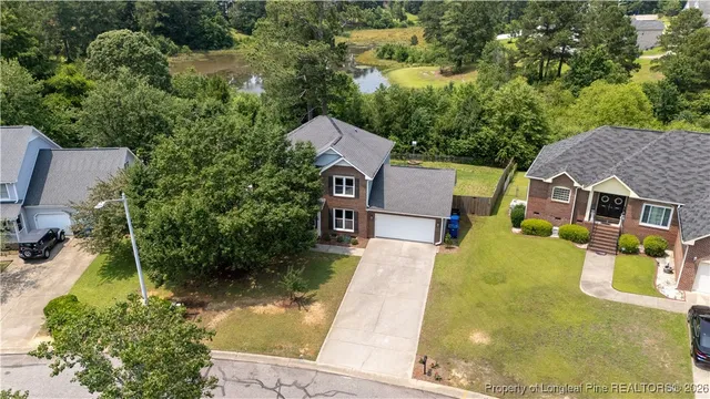 an aerial view of a house with swimming pool and large trees