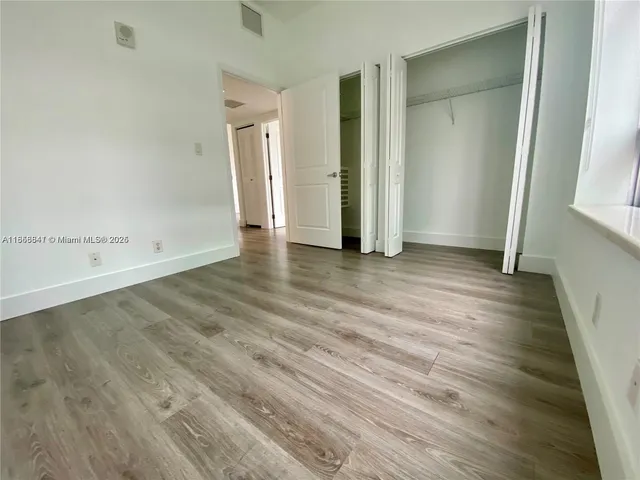 an empty room with wooden floor and closet