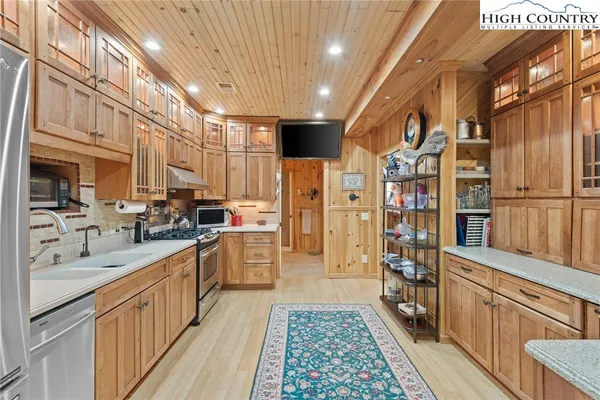 a kitchen with stainless steel appliances granite countertop a refrigerator a oven and white cabinets with wooden floors