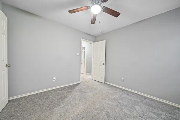 an empty room with chandelier fan and window