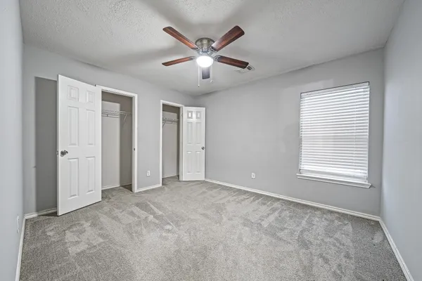 a view of an empty room with window and a ceiling fan