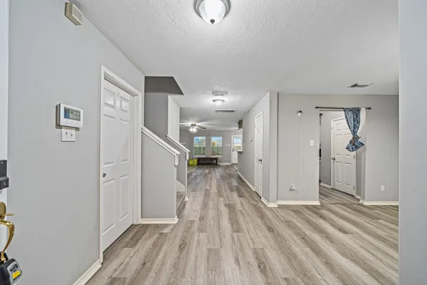 a view of a hallway with wooden floor and a bathroom