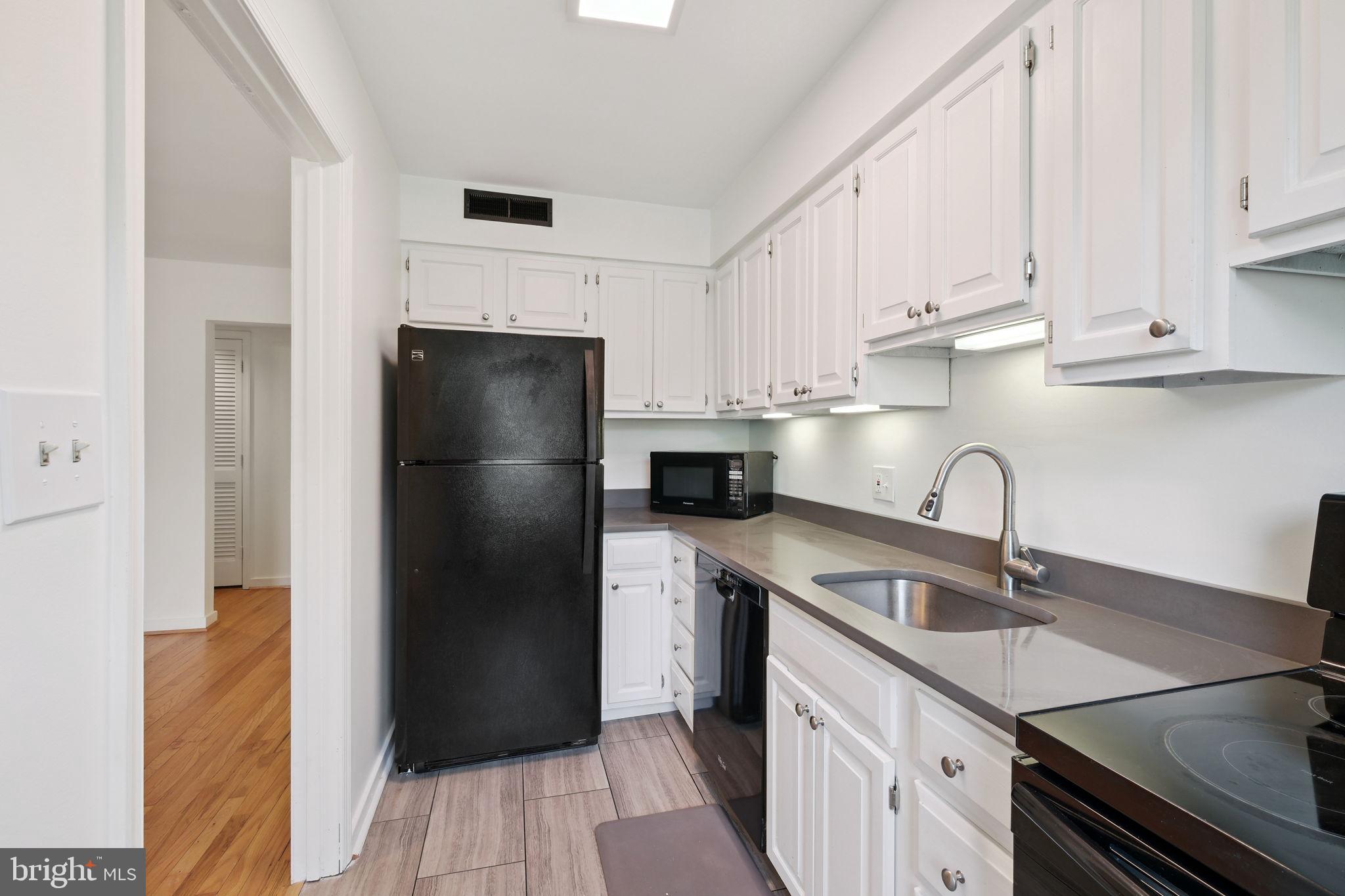 8203 Grubb Road, Unit 201 Silver Spring, MD 20910 - Photo 8 of 26 a kitchen with a sink a refrigerator and cabinets